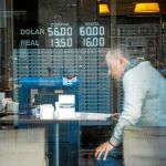 Un hombre lee en un bar frente a una pizarra con el valor del dólar y del real en otra jornada de incertidumbre en Argentina