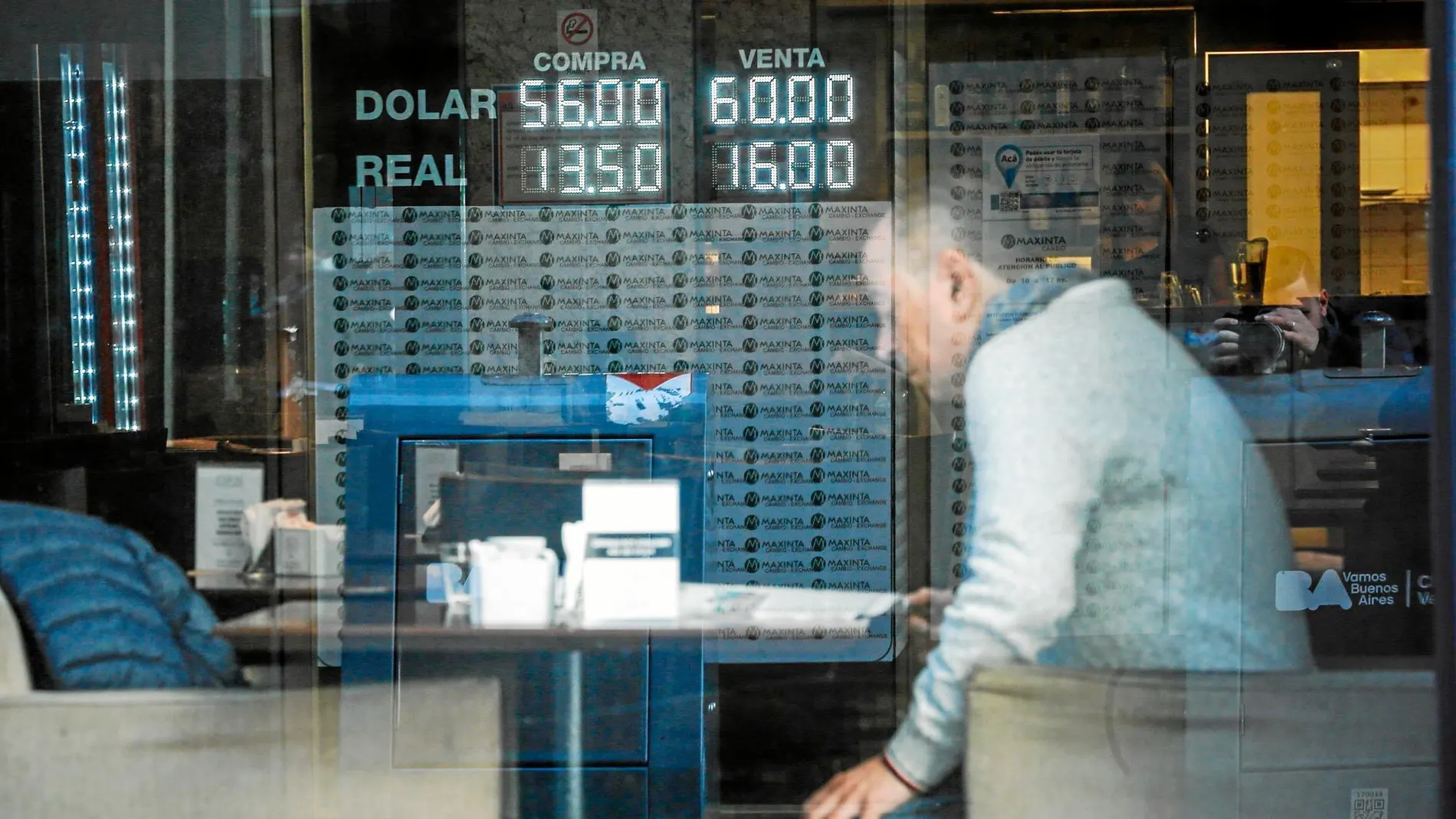 Un hombre lee en un bar frente a una pizarra con el valor del dólar y del real en otra jornada de incertidumbre en Argentina