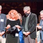 La ganadora del Premio Nobel Ig Dra. Elena Bodnar demuestra su invento (un  sujetador que se puede convertir rápidamente en un par de máscaras protectoras ) con la ayuda de los premios Nobel Wolfgang Ketterle (izquierda), Orhan Pamuk y  Paul Krugman  (derecha), en la ceremonia de 2009