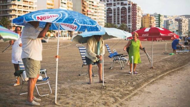 Imagen de archivo de varias personas mayores colocando las sombrillas a primera hora de la mañana