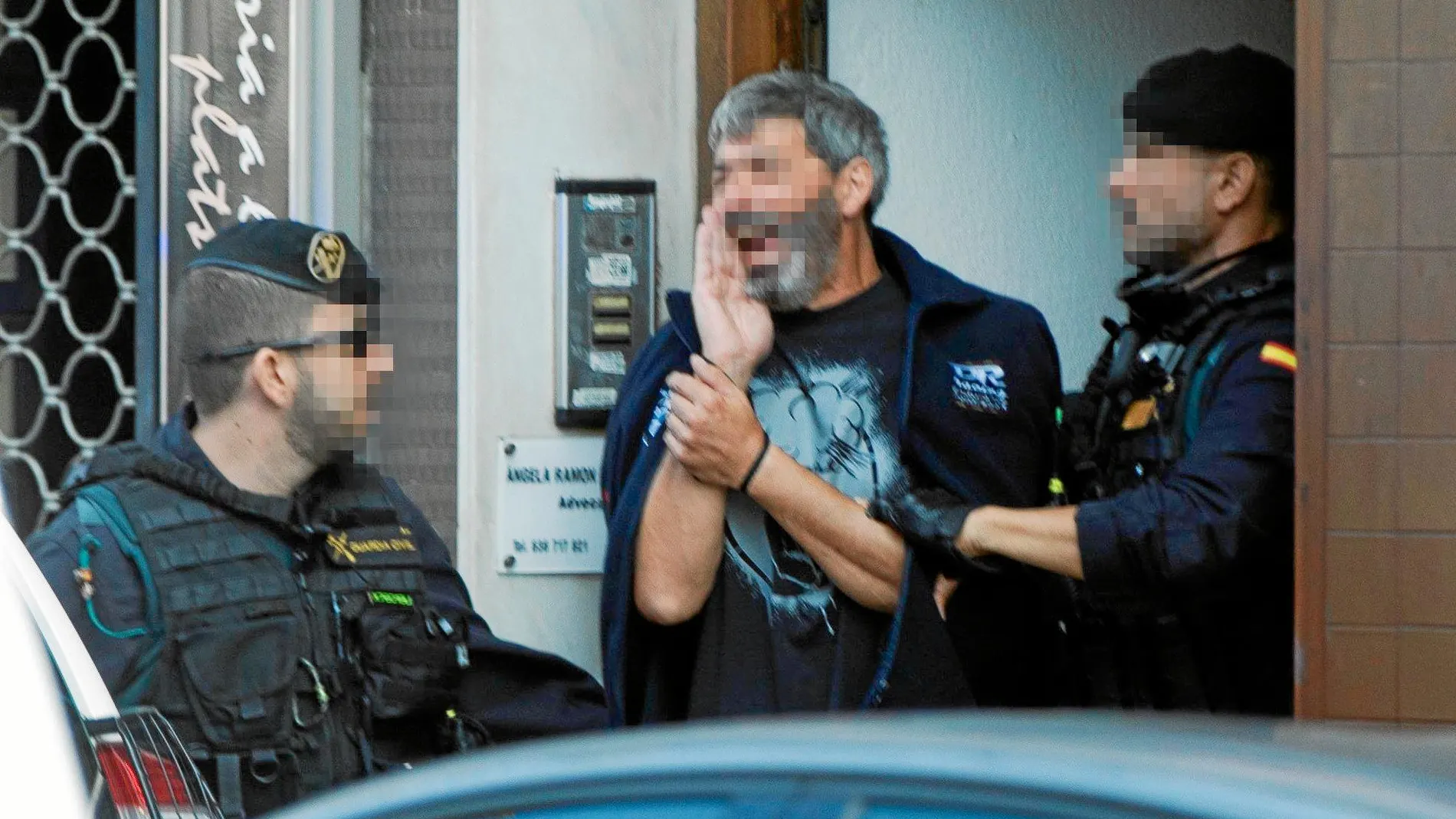 Agentes de la Guardia Civil acompañan a uno de los nueve detenidos entre insultos de grupos independentistas