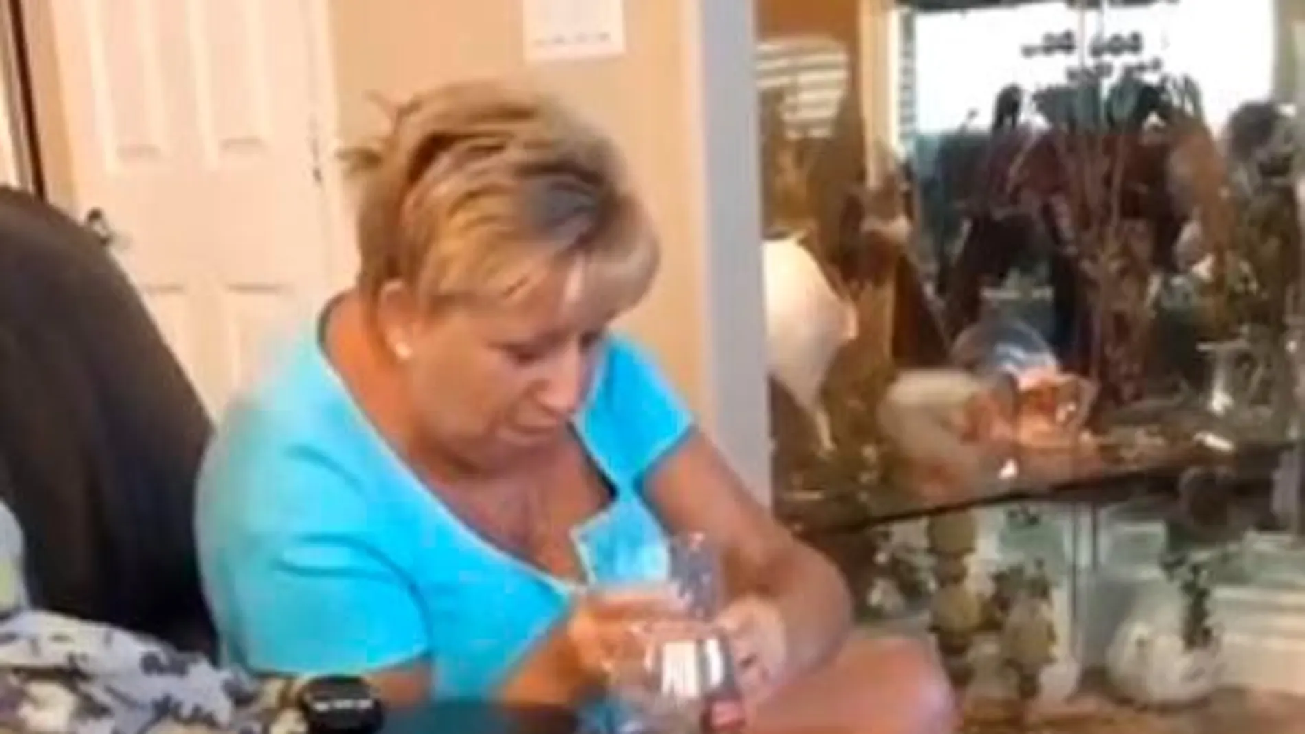 Imagen de la abuela en el momento en el que trata, con gran dificultad, de dejar el vaso de agua en el reposabrazos
