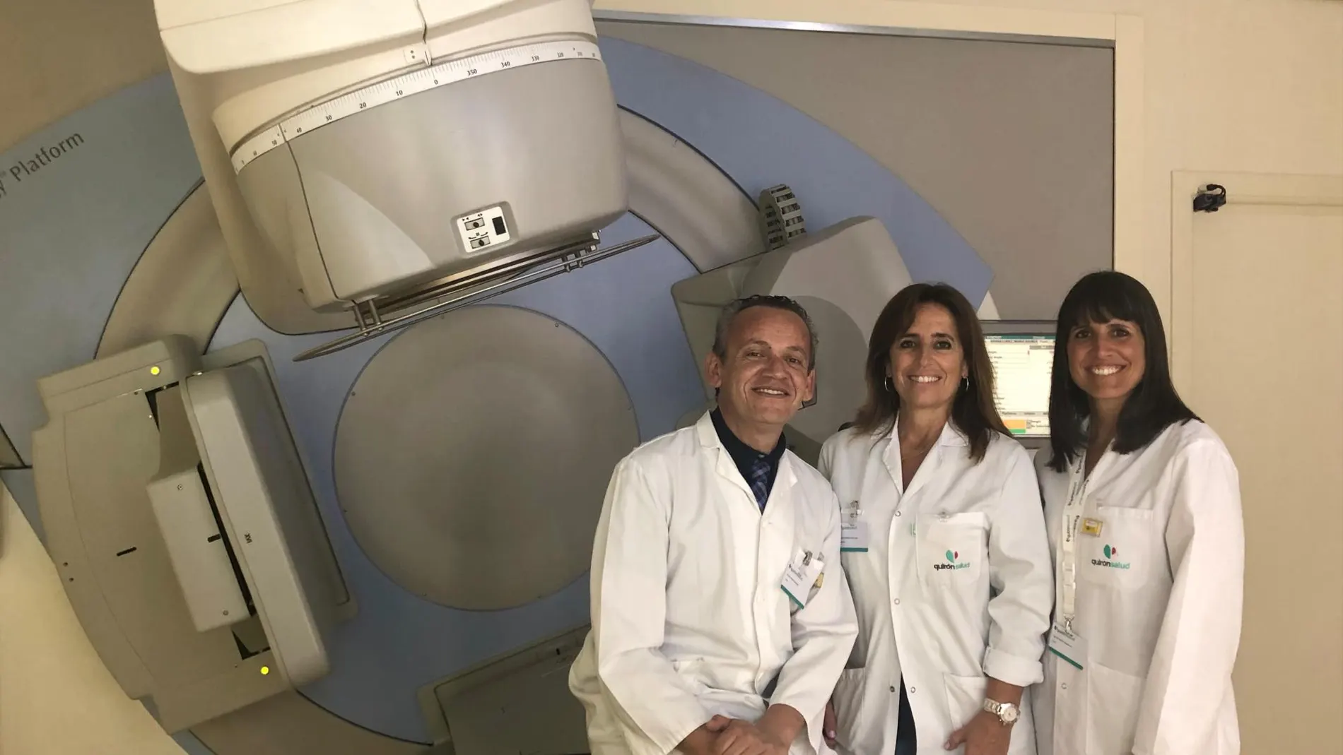 De izquierda a derecha, el radiofísico Rafael Linares, la radioterapeuta Julia Montañés y la radiofísica Beatriz Mateo, junto a uno de los aceleradores lineales del Servicio de Radioterapia del centro hospitalario / La Razón