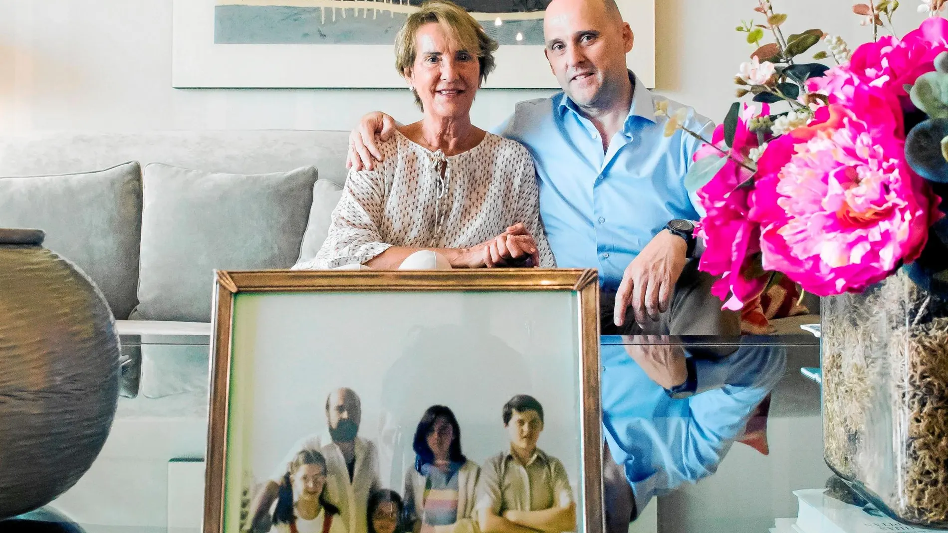 Charo Muela posa junto a uno de sus hijos ante una fotografía de toda la familia antes de que ETA asesinara a su marido / Efe