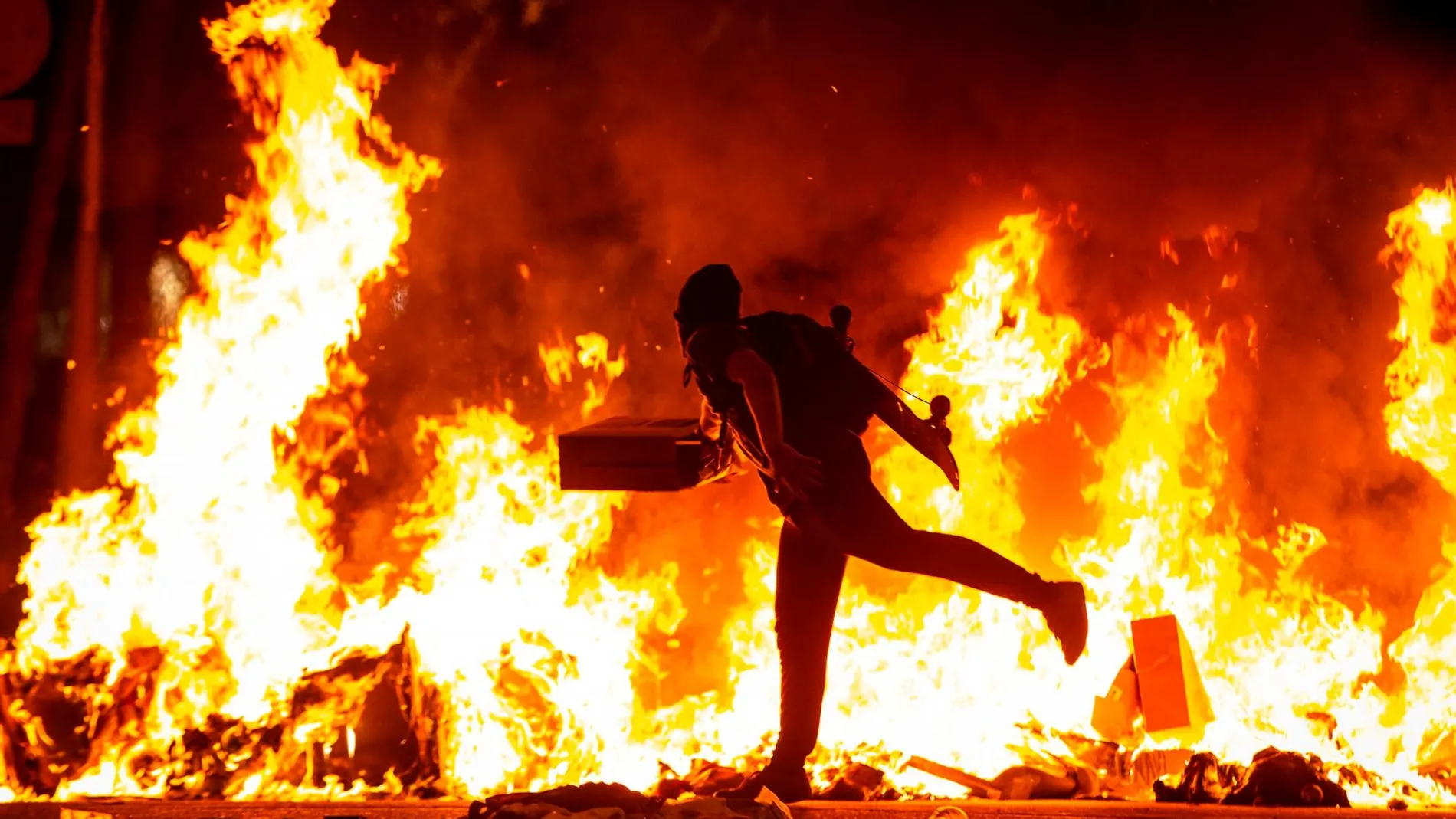 Un manifestante echa al fuego un cartón junto a la Delegación del Gobierno en Barcelona durante los incidentes producidos en la noche de ayer / Foto: Efe-Enric Fontcuberta