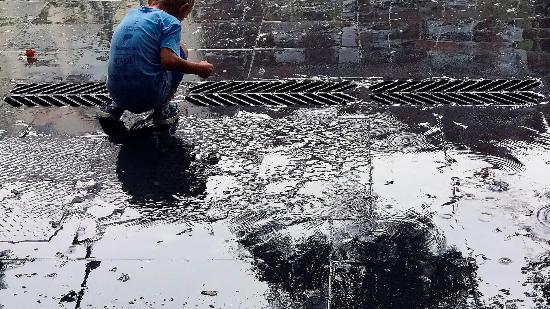 Un niño juega con el agua en una plaza de Barcelona/Efe