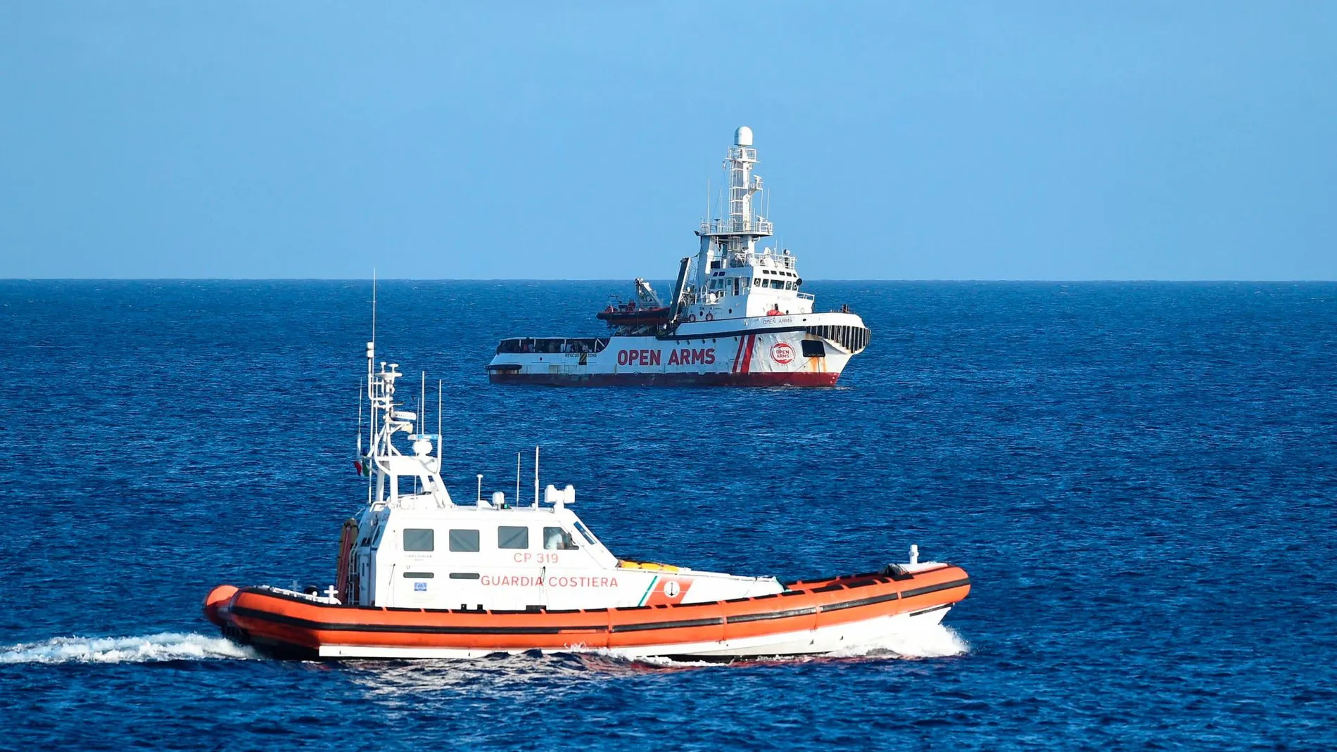 El barco de Open Arms siendo vigilado por una unidad de la guardia costera italiana