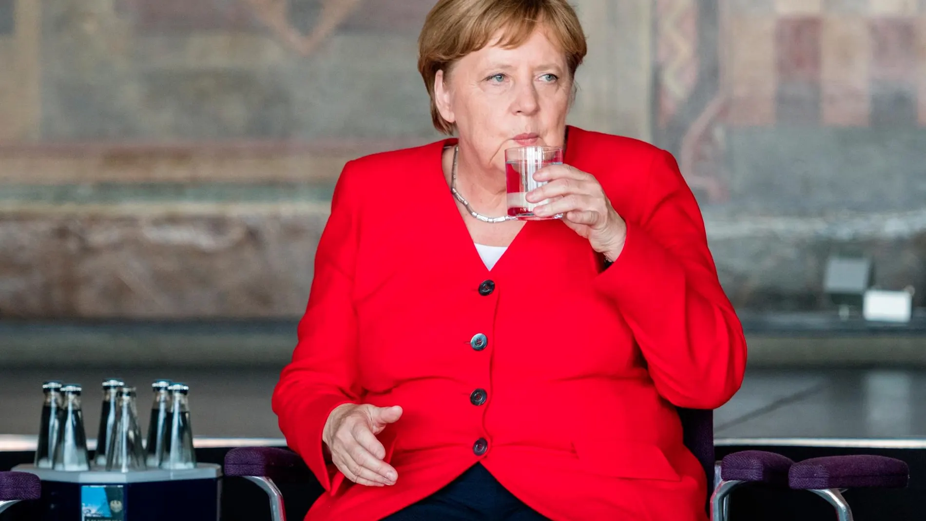 Angela Merkel con un vaso de agua y seis botellas/ EFE