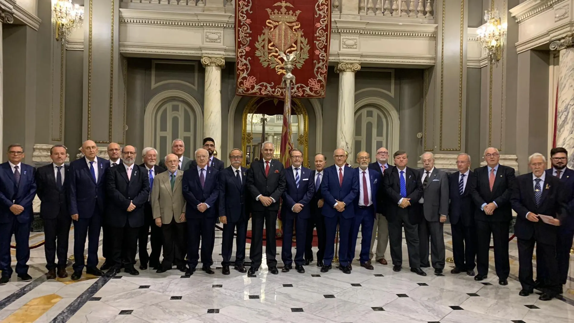 Los miembros del Centenar de la Ploma posan en el Ayuntamiento de Valencia delante de la real Senyera