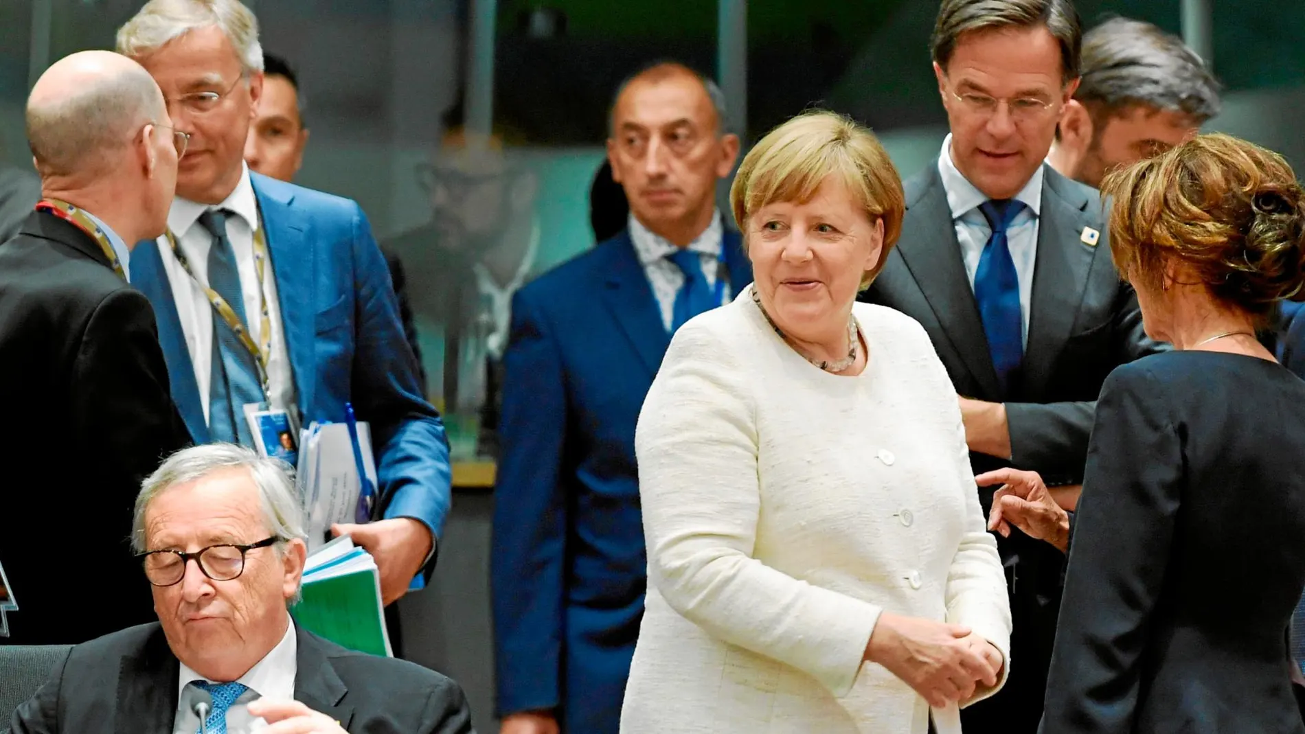 Jean-Claude Juncker, presidente del Ejecutivo comunitario, permanece sentado en presencia de Angela Merkel
