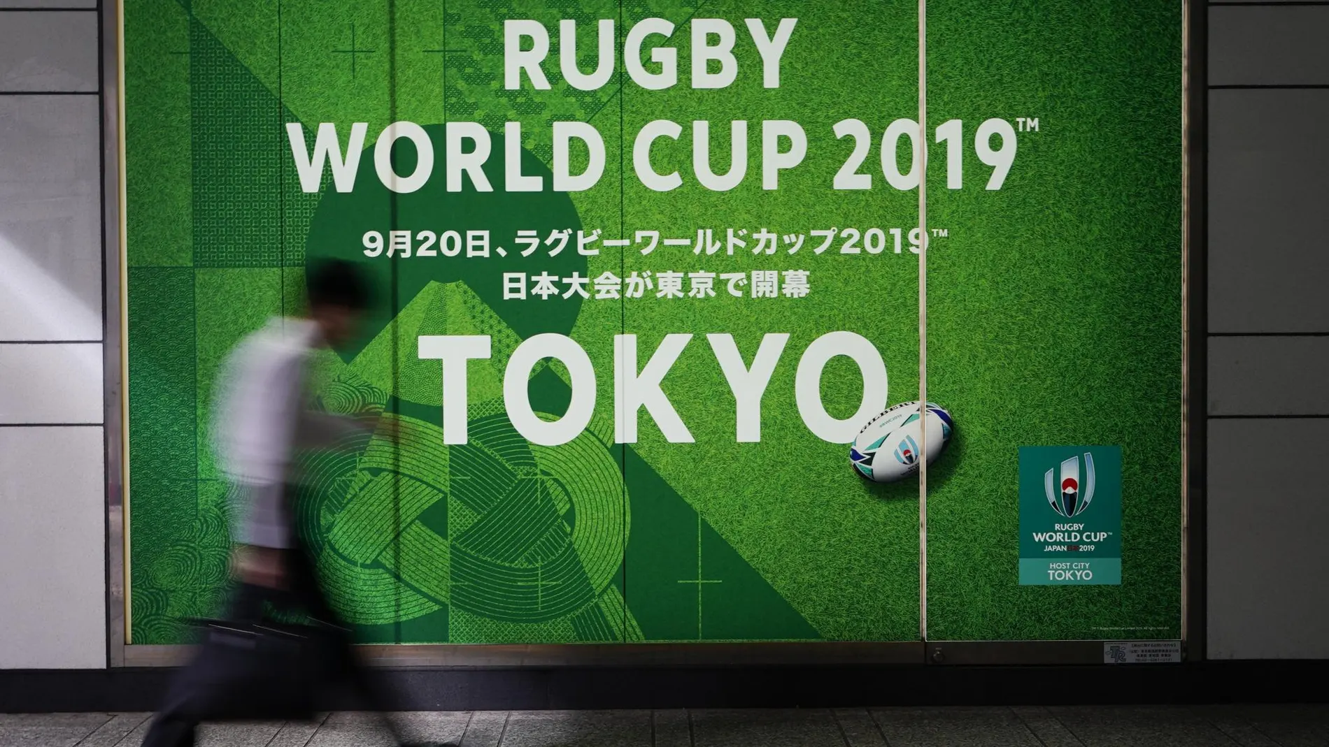 [A man walks past a sign promoting the Rugby World Cup Thursday, Oct. 10, 2019, in Tokyo][The powerful typhoon that has caused the first cancellation of the Rugby World Cup games has ended Italy's]
