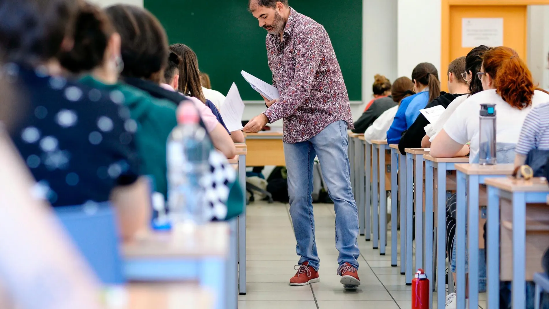 Un profesor recoge los trabajos de sus alumnos