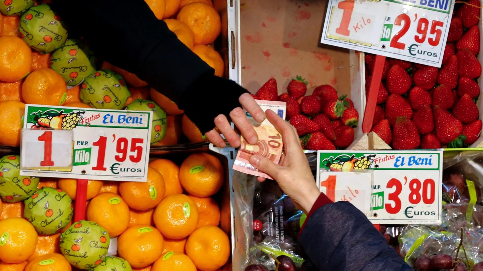 Una persona compra en una frutería de un mercado de Sevilla