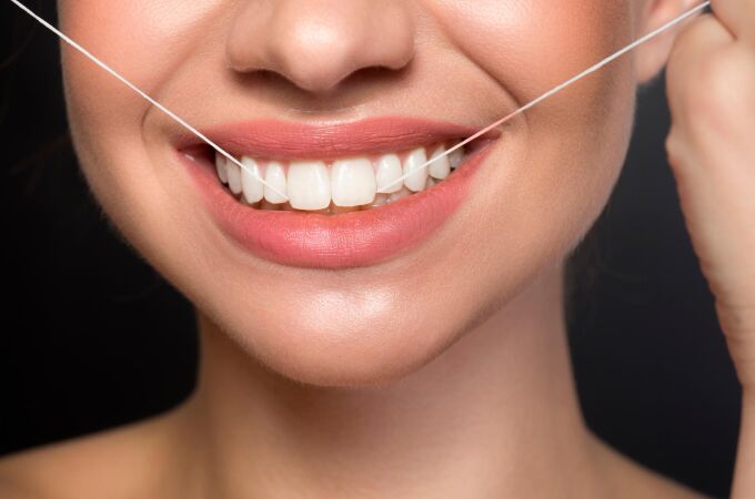Una mujer utilizando hilo dental