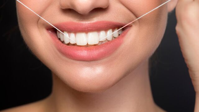 Una mujer utilizando hilo dental