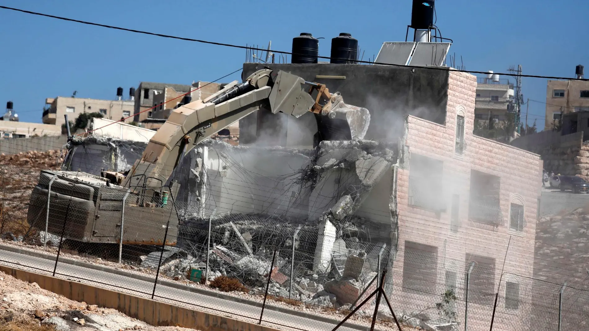 Una excavadora destruye un bloque construido junto al muro de separación con la parte israelí/Efe
