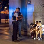 Dos agentes de los Mossos d'Esquadra proceden a identificar a un grupo de jóvenes en Barcelona durante la noche