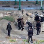 Miembros de las fuerzas de seguridad detienen a un inmigrante que saltó la valla que separa Ceuta de Marruecos
