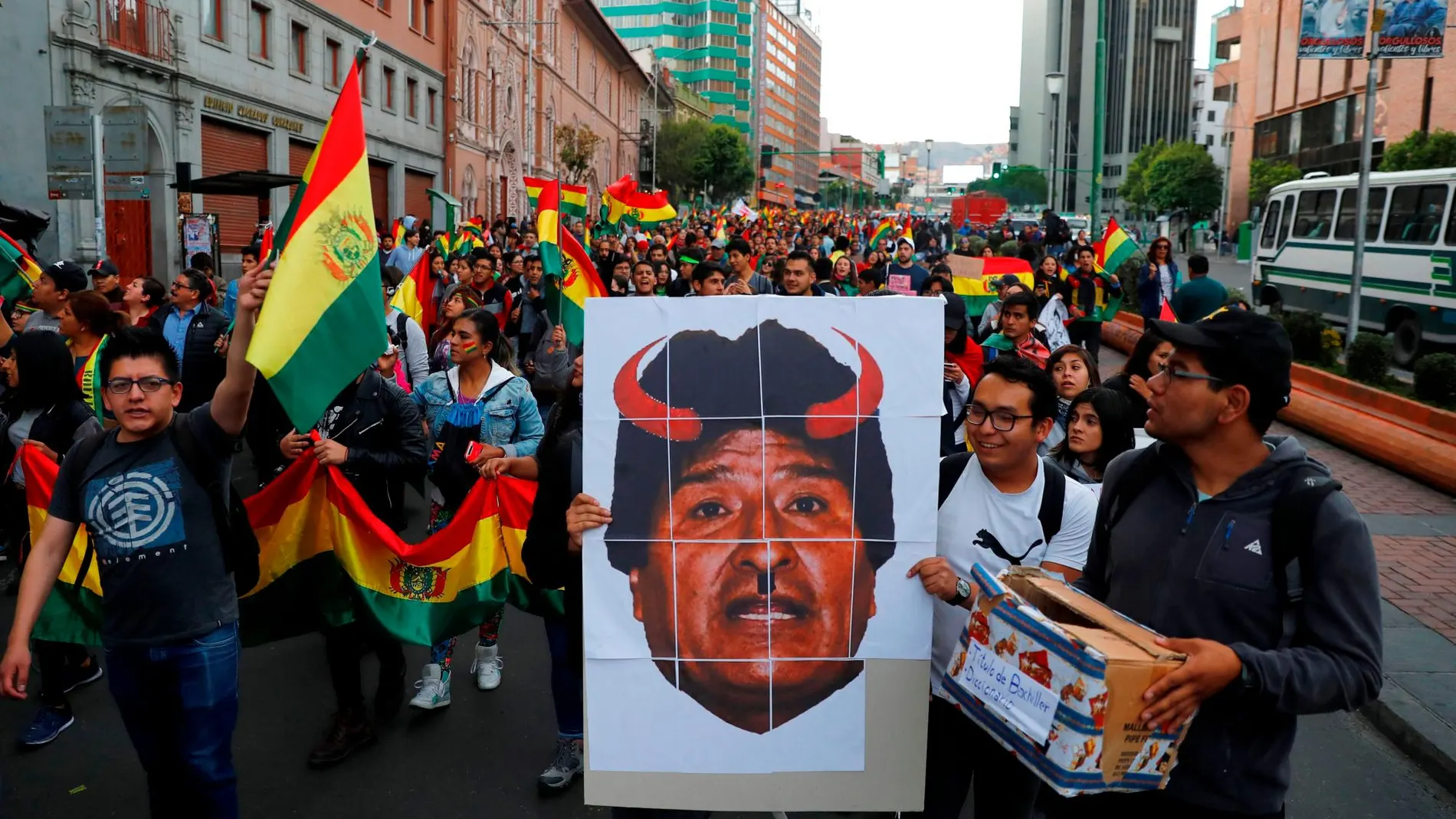 Manifestantes llevan una pancarta con el rostro de Evo Morales con cuernos rojos en una marcha de protesta en La Paz / Reuters