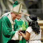 Una niña indígena entrega al Papa una planta como ofrenda, ayer en la misa tras el Sínodo / Ap