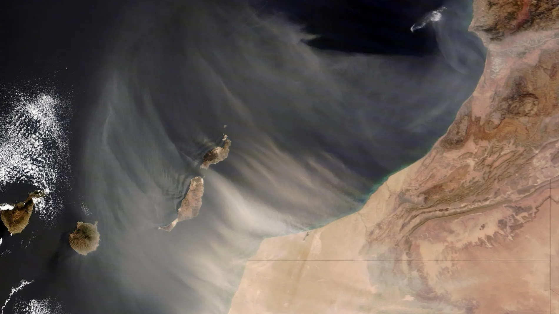 Fotografía, facilitadas por la NASA, de una calima de polvo del Sahara cubriendo las Islas Canarias capturada por satélite.