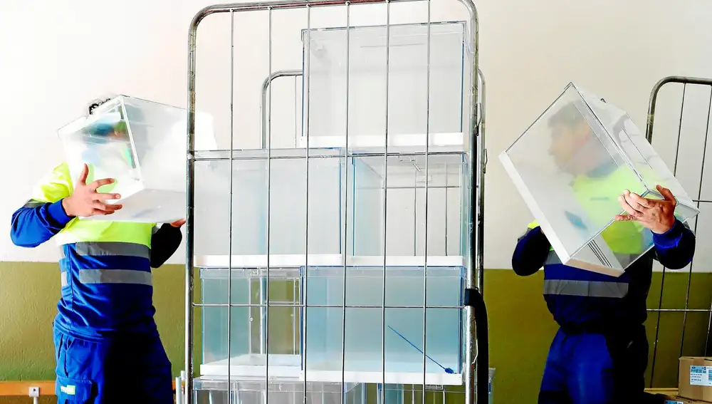 Dos operarios descargan urnas para el domingo electoral