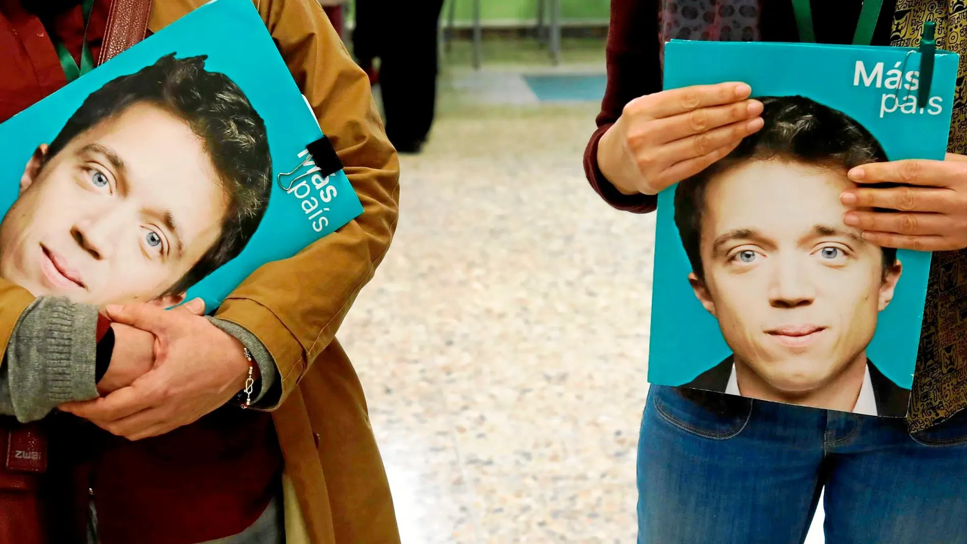 Dos simpatizantes de Más País con carteles de su líder en la puerta de un colegio electoral en Madrid. Foto: Reuters