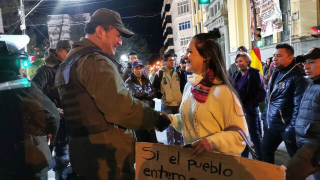 Una estudiante universitaria y un agente de Policía se dan la mano durante una protesta en Oruro, Bolivia