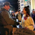 Una estudiante universitaria y un agente de Policía se dan la mano durante una protesta en Oruro, Bolivia