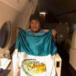 El ex presidente de Bolivia Evo Morales sostiene una bandera mexicana en un avión