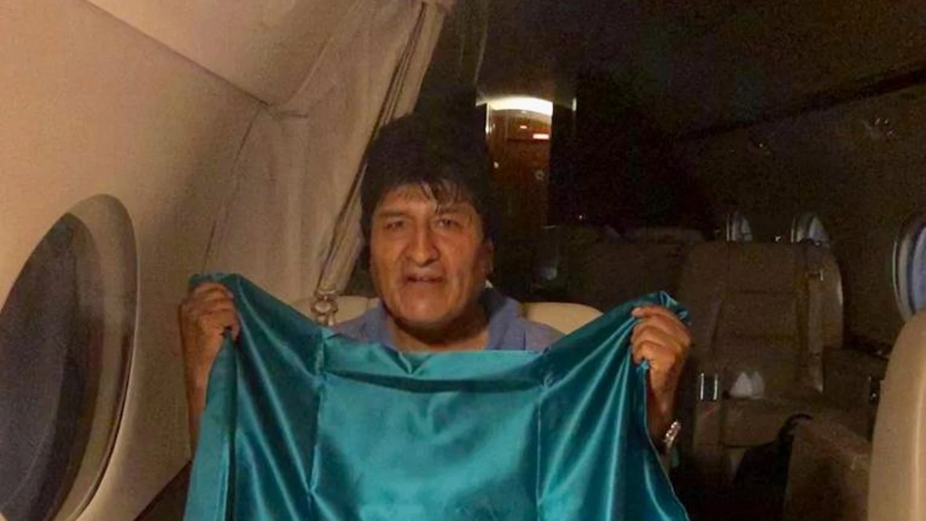 El ex presidente de Bolivia Evo Morales sostiene una bandera mexicana en un avión