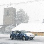 Un vehículo circula por la localidad leonesa de Pandorado ante un temporal.