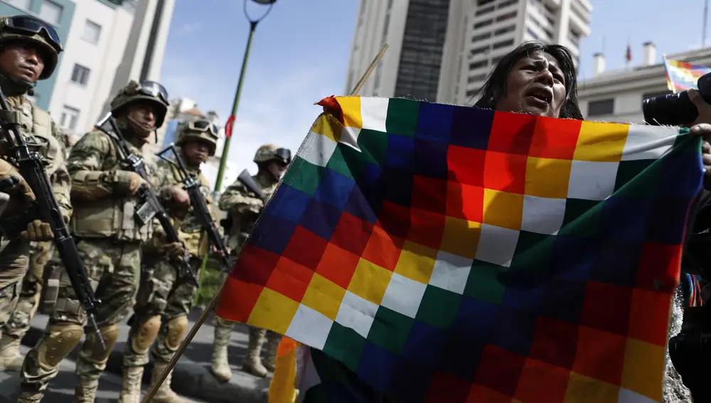 Un seguidor del ex presidente Morales porta una banderaA backer of former President Evo Morales porta una bandra Wiphala frente a un soldado en La Paz, Bolivia.