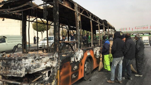 Varios curiosos contemplan un autobús incendiado en la ciudad de Isfahan durante las protestas de la pasada noche