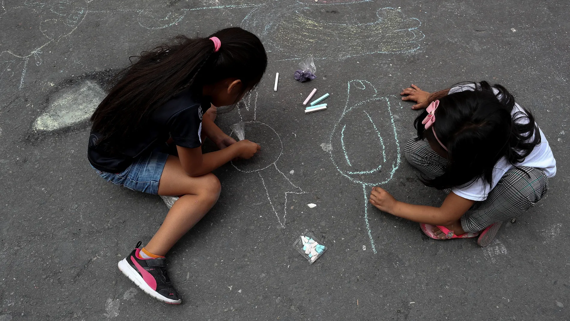 Dos niñas dibujan en la calle