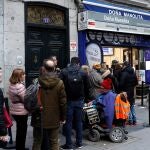 Varias personas hacen cola a la puerta de la administración de lotería Doña Manolita en Madrid.