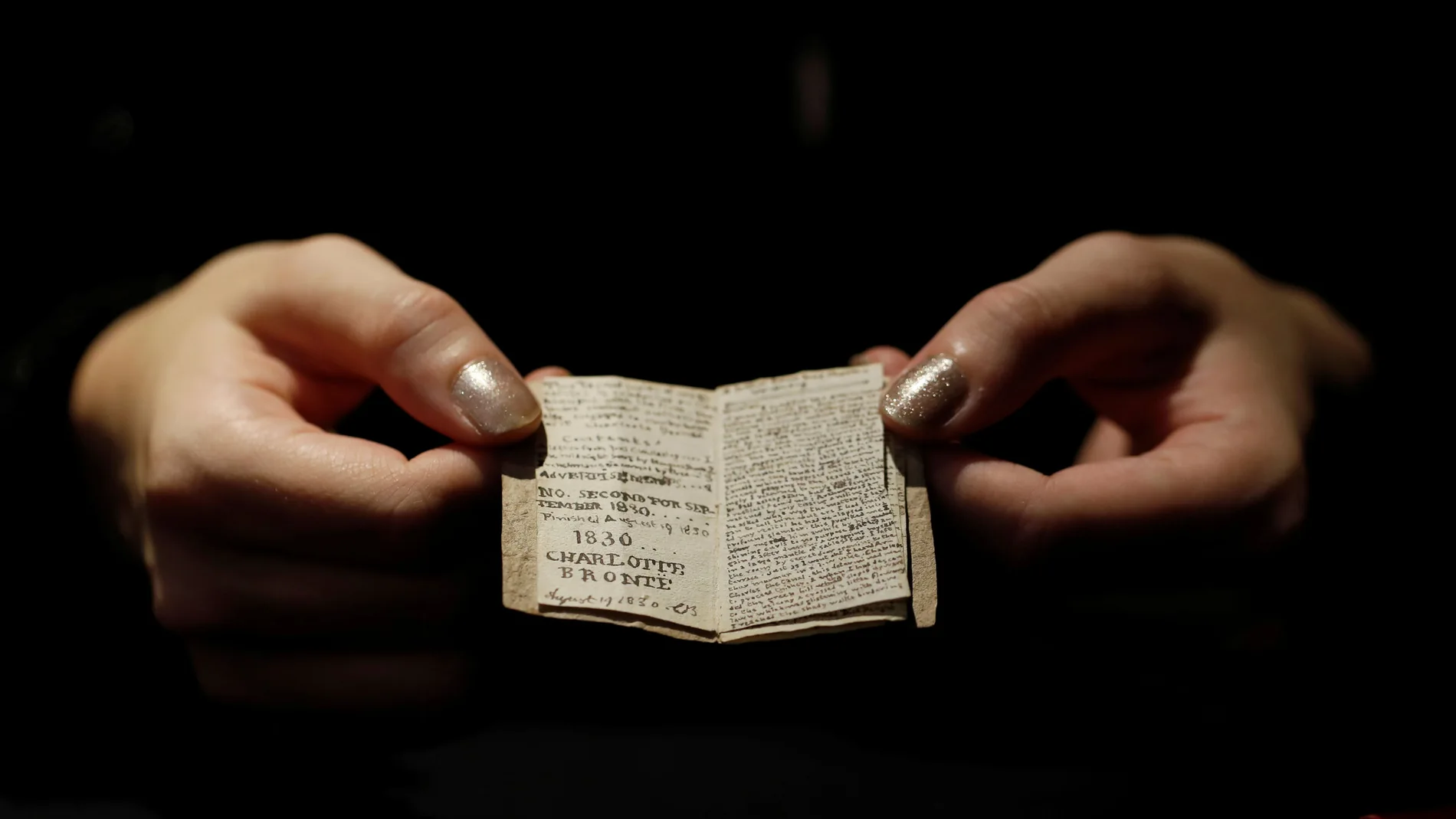 An employee displays the second issue of Young Men's Magazine, a miniature manuscript dated 1830, written by Charlotte Bronte when she was 14 years old, before being put on auction at Drouot auction house in Paris