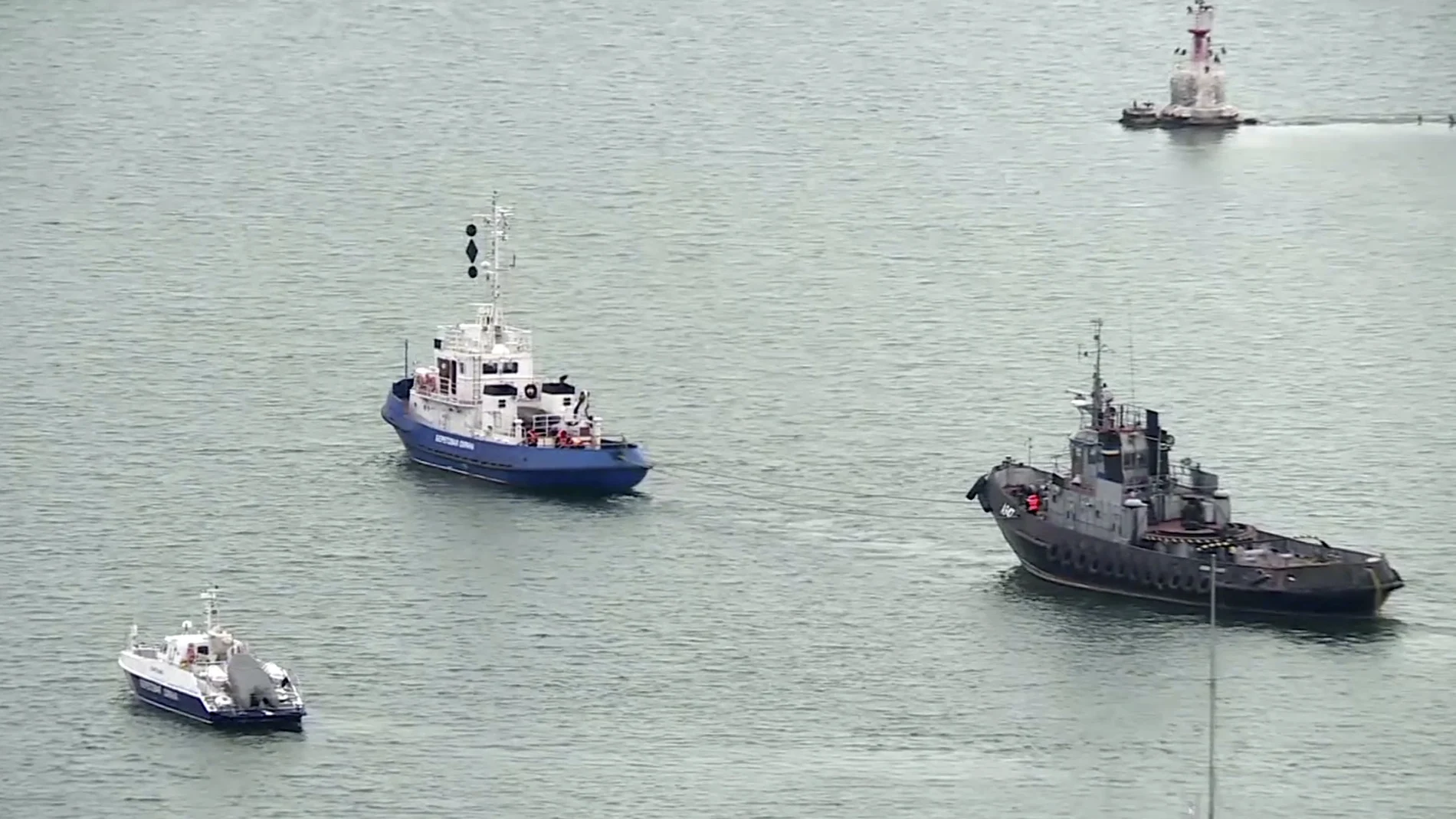 This video grab provided by the Krym 24 tv station via AP Television shows a seized Ukrainian ship, right, is towed by a Russian coast guard boat out of the port in Kerch, Crimea, Sunday, Nov. 17, 2019. Russia's Foreign Ministry says three Ukrainian naval ships that were seized in a shooting confrontation nearly a year ago have been returned. (Krym 24 tv station via AP Television)