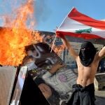 Un manifestante con la bandera libanesa junto a un fuego que bloquea la carretera que lleva al Parlamento