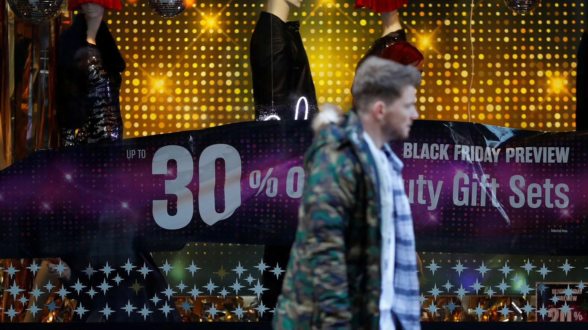 A man walks past a sign advertising Black Friday offers at a House of Fraser store in Manchester, Britain