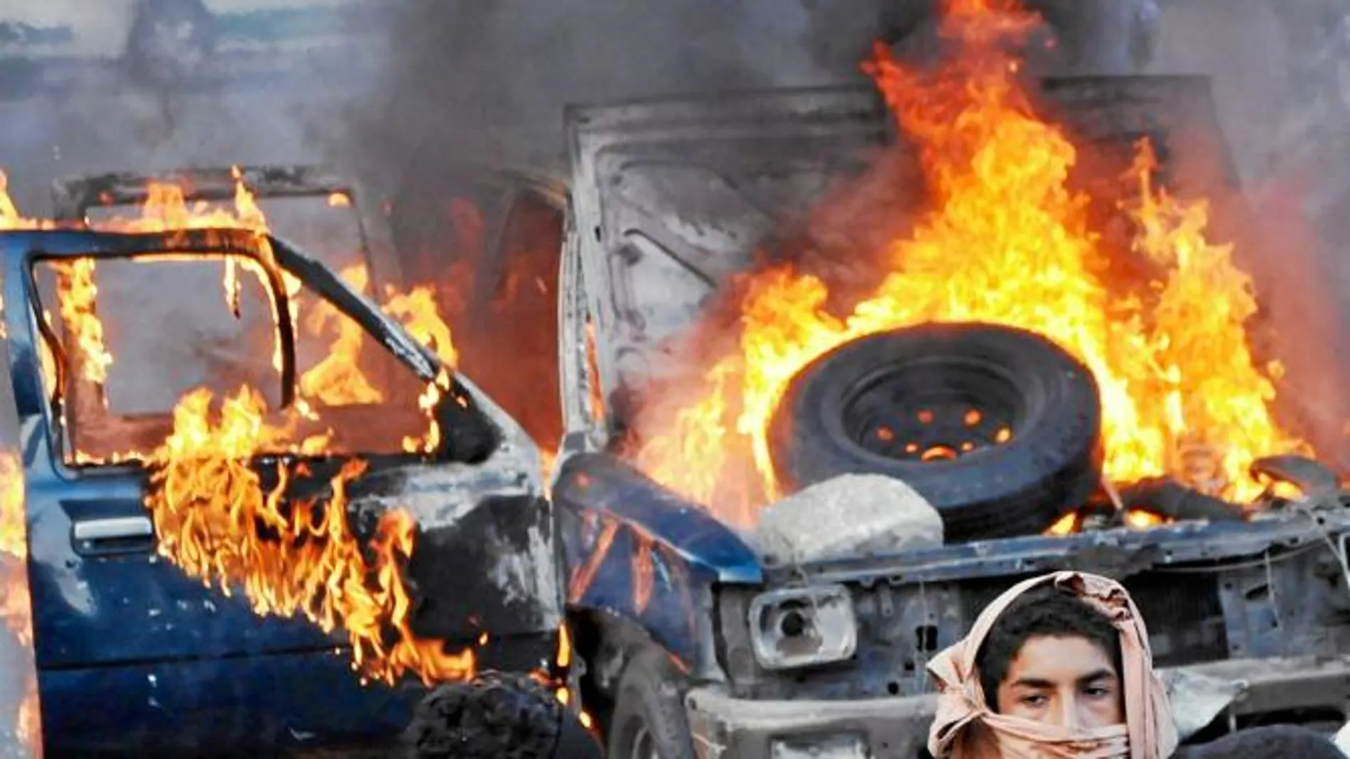 Egipcios junto a un coche quemado ayer en El Cairo
