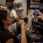 Una persona que sostiene dolores en su mano para realizar el pago por su compra en una tienda de un centro comercial, en Caracas