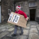 Un hombre en Edimburgo (Escocia) traslada un cartel a la puerta de un colegio electoral
