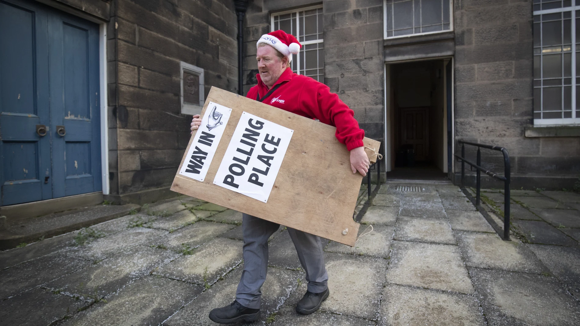 Un hombre en Edimburgo (Escocia) traslada un cartel a la puerta de un colegio electoral