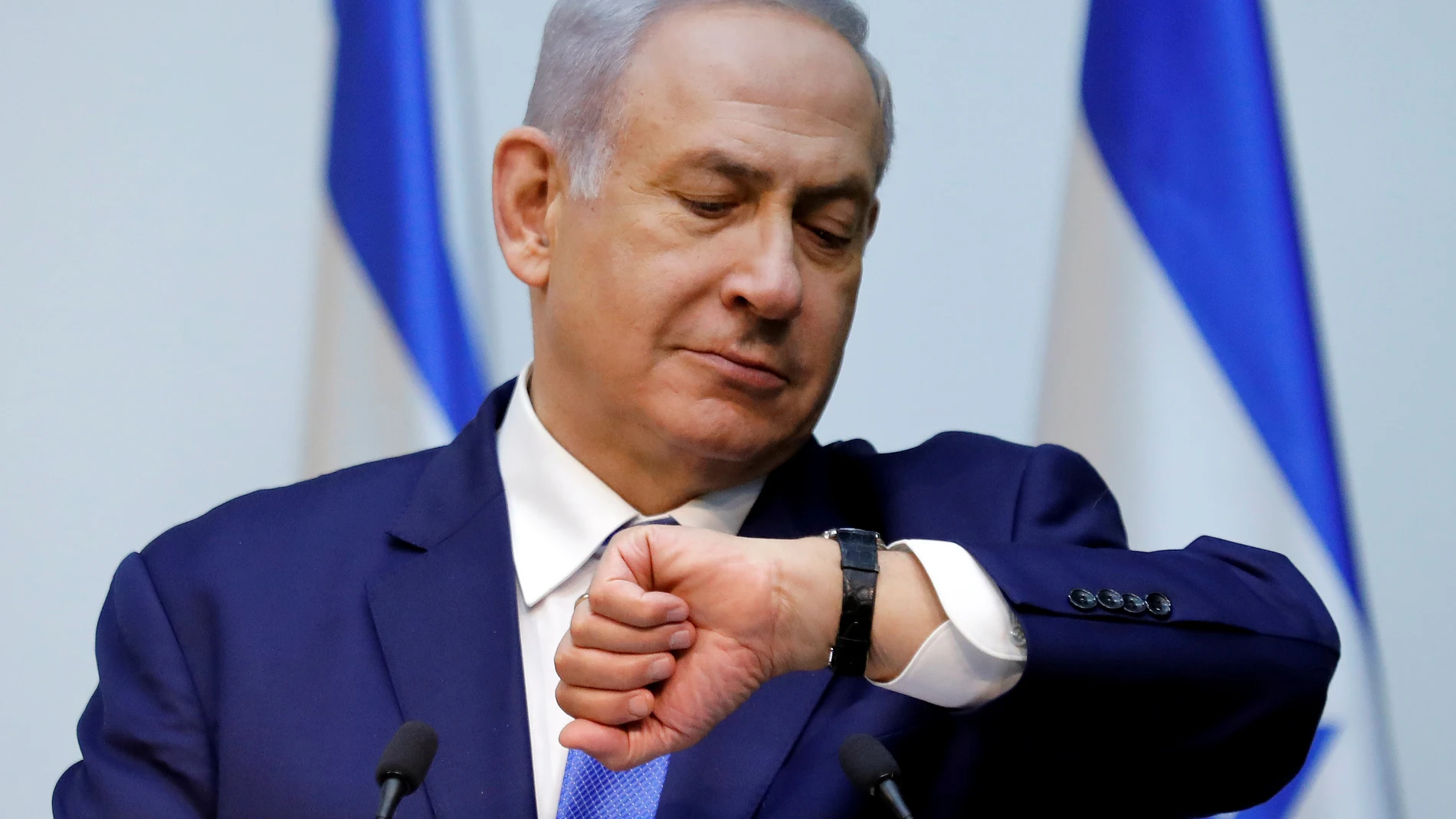FILE PHOTO: Israeli Prime Minister Benjamin Netanyahu looks at his watch before delivering a statement at the Knesset, Israel's parliament, in Jerusalem