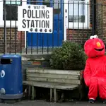 Una persona disfrazada de Elmo espera sentada en una centro electoral en Londres.