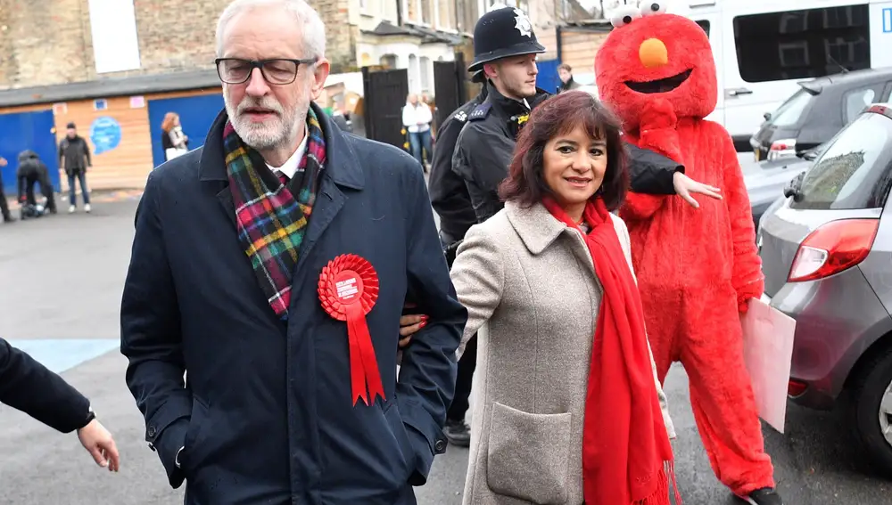 El líder de la oposición, Jeremy Corbyn y su esposa, Laura Alvez son perseguidos por una persona disfrazada de Elmo a su llegada al colegio electoral ayer en Londres.