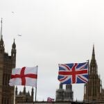 Una bandera inglesa y otra británica ondean frente al palacio de Westminster en Londres. (AP Photo/Thanassis Stavrakis)
