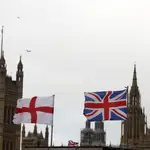 Una bandera inglesa y otra británica ondean frente al palacio de Westminster en Londres. (AP Photo/Thanassis Stavrakis)