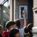 Un comprador de lotería pasa sus décimos por la imagen de un gato negro en Sevilla